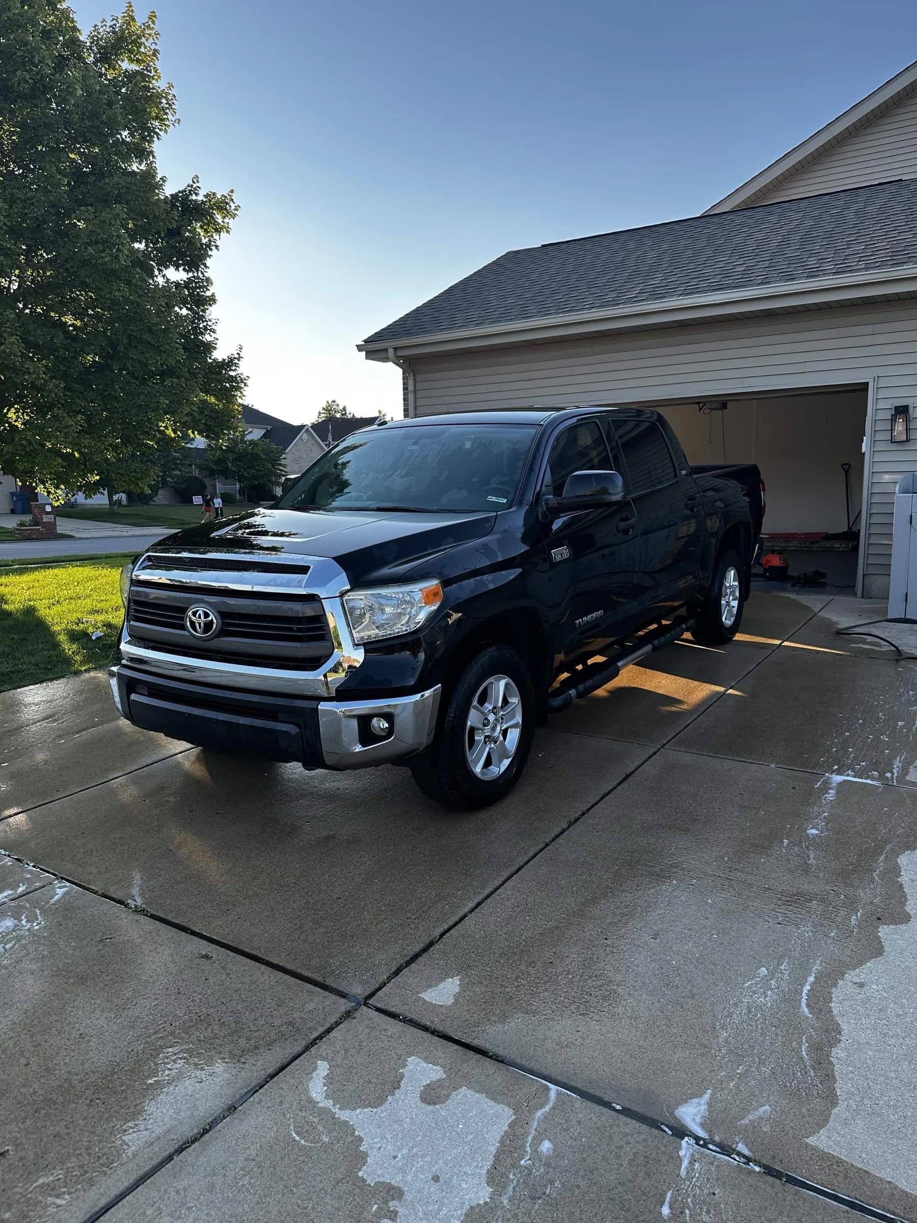 Black pickup truck shining on a wet residential driveway
